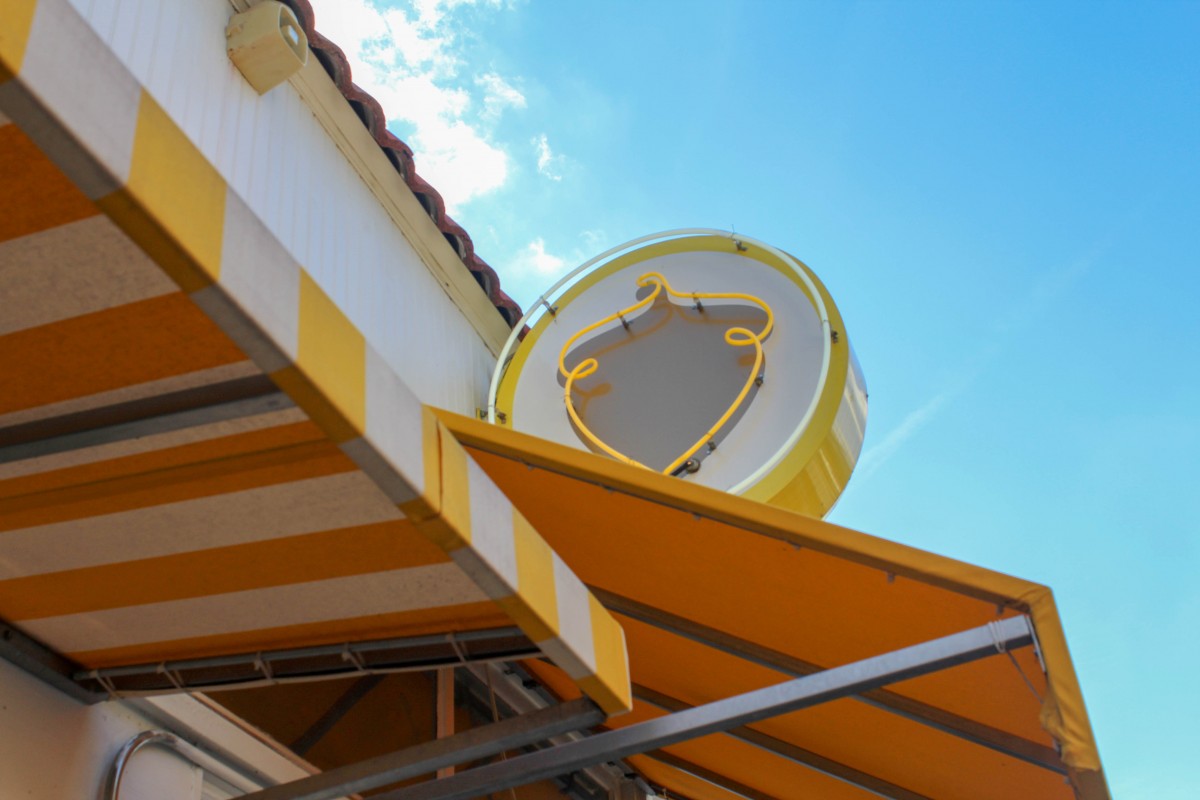 A picture of a yellow awning with an acorn logo in Bishop Arts District.