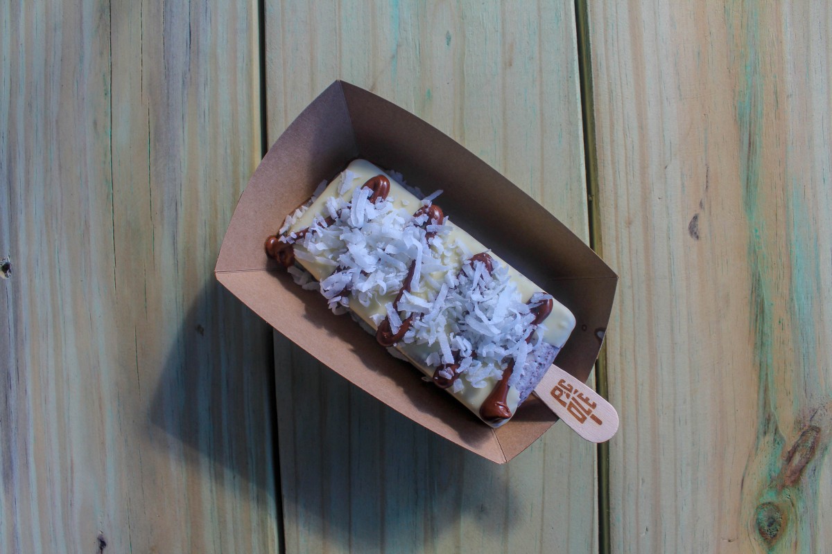 This is a photo of a pop from Picole Pops in Bishop Arts District. The pop is a pale yellow with a spread of nutella and coconut shavings on top.