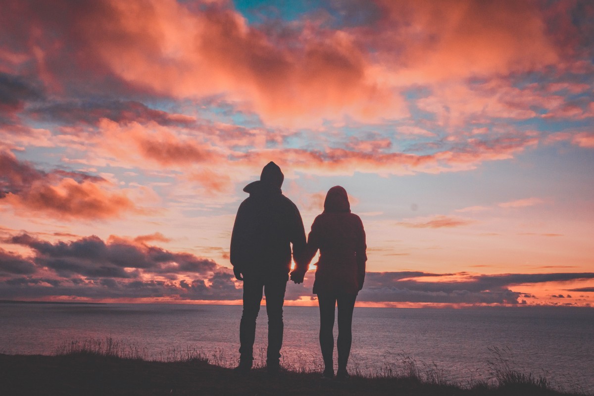 road trip questions for couples - couple holding hands at sunset