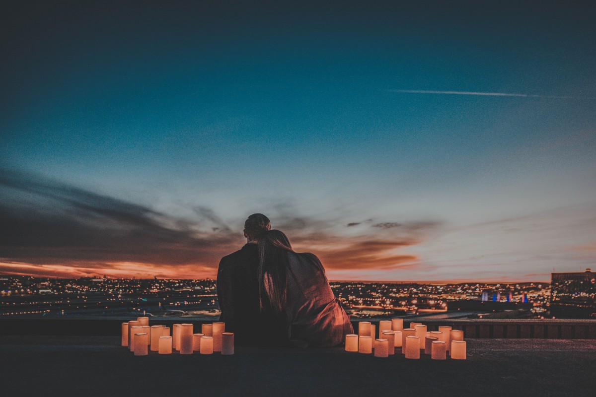 couple at sunrise with small lamps surrounding them - road trip questions for couples