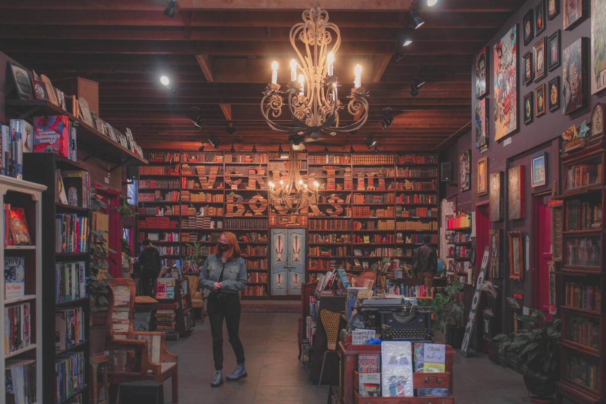 interior of Verbatim Books with decorative book display - used book shelves and seating shown below two chandeliers