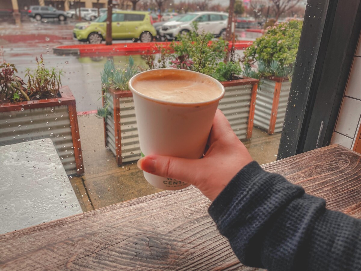 holding up a cup of Spectra coffee in San Jose