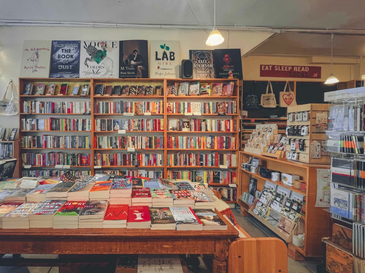 inside Folio Books, a Noe Valley community bookstore serving the San Francisco area: desk of books, three shelves, journals, register